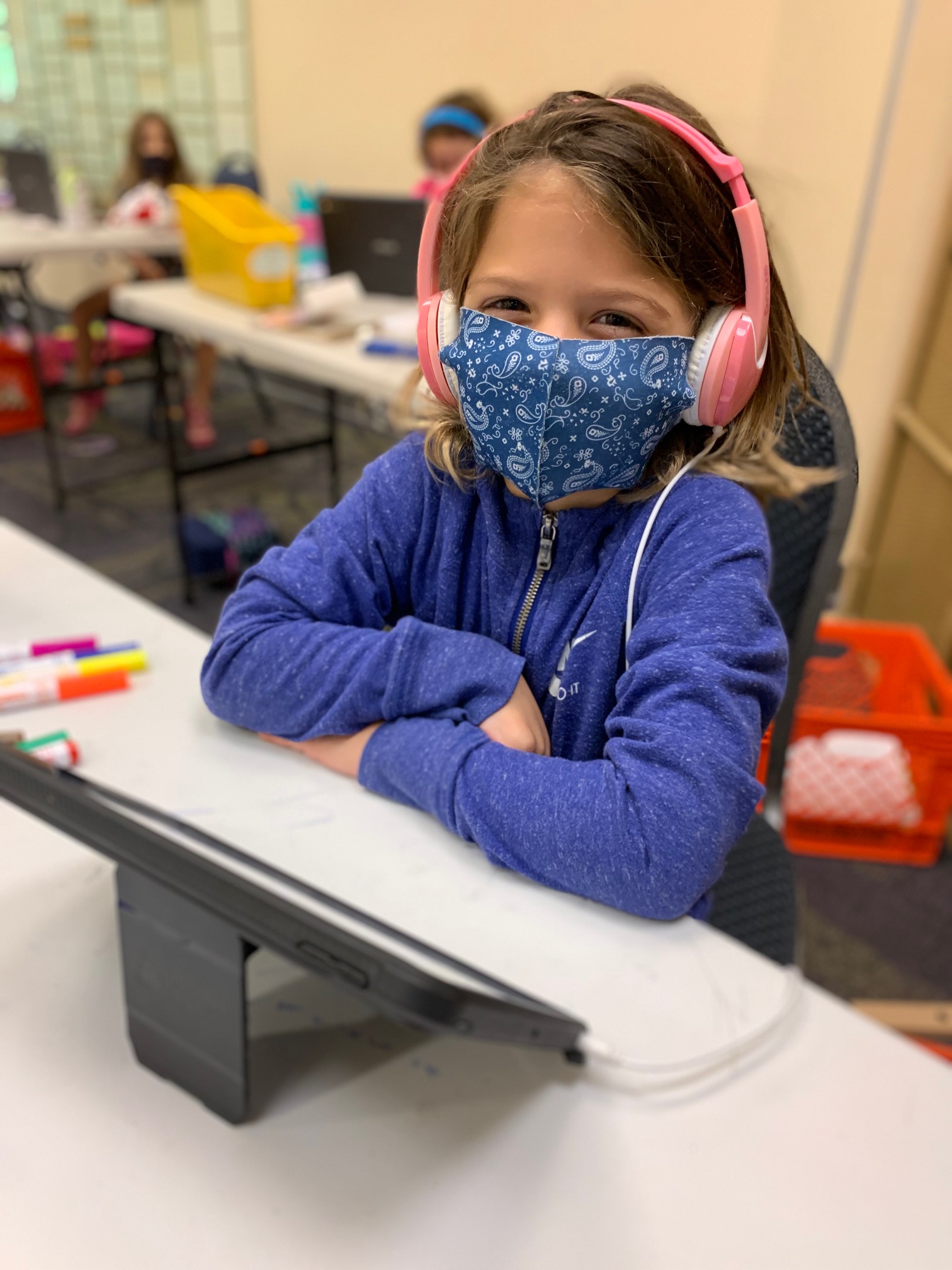 A young student smiles behind her mask at the JCC.