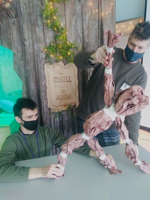 Two puppeteers move a puppet made of brown paper and tape at the Chill Project.