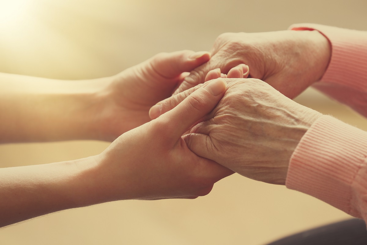 A young person and old person hold hands.